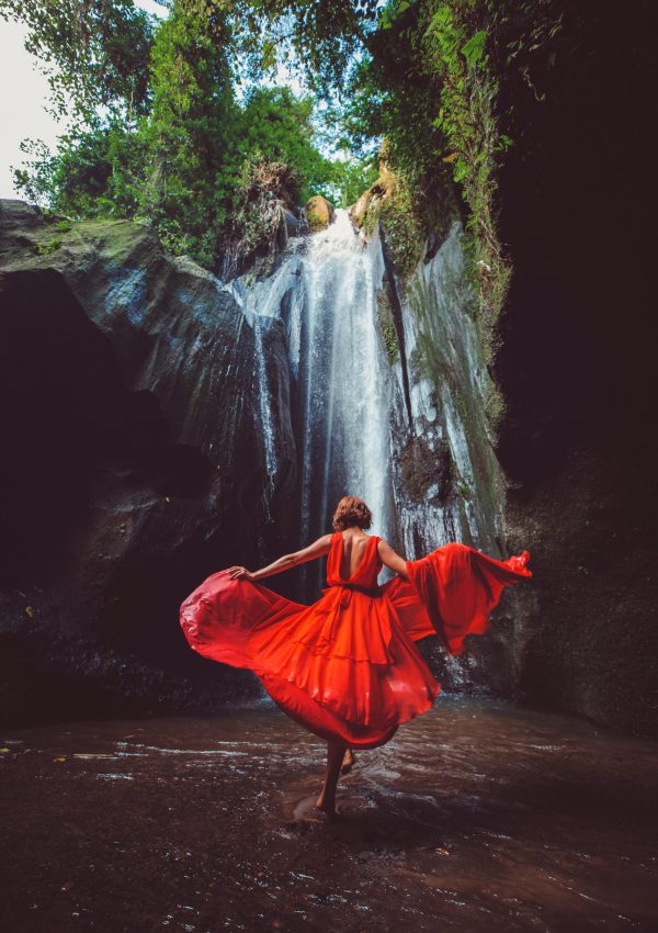 girl in a red dress dancing in a waterfall. high quality photo